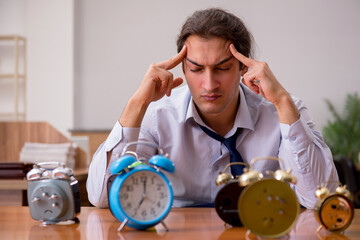 Young male employee sleeping in the office in time management co
