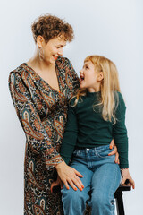 portrait of single mother and her daughter looking at each other against white background