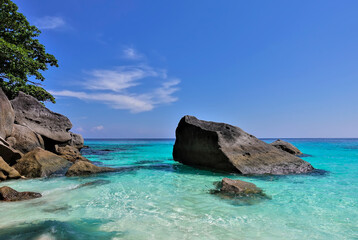 Fototapeta premium The aquamarine Andaman Sea is clear and calm. Huge picturesque boulders protrude from the water. White clouds in the azure sky. Thailand. Similan Islands.