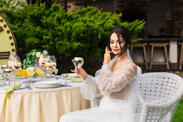 Young woman wearing a white dress, holding a glass of champagne