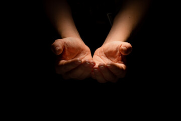 Begging, empty palms, outstretched hands. Concept of social disadvantage, black background.