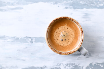 Coffee in glass cup on bright wooden background. Top view.