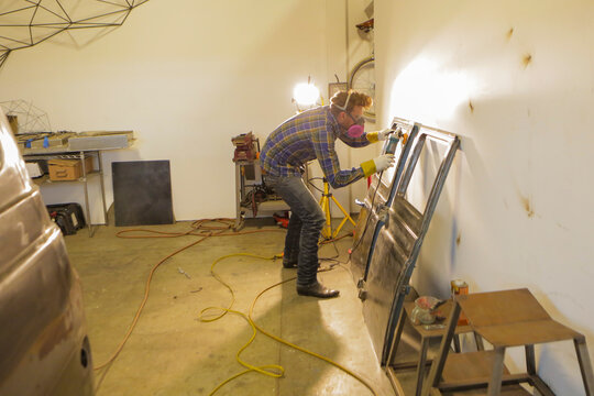 Engineer polishing van doors with angle grinder in factory