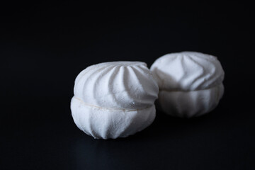 Two vanilla marshmallows on a black background close-up.