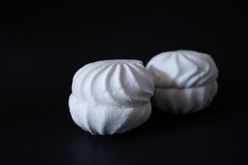 Obraz premium Two vanilla marshmallows on a black background close-up.