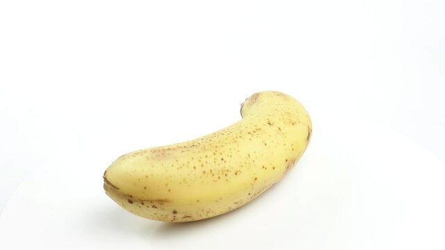 Ripe yellow banana rotates hanging on a white background, isolated