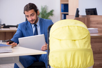 Young male employee looking after new born at workplace