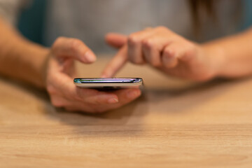 woman sits at a table and uses her smartphone to plot a route or search for information on the Internet.