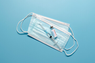 Ampoule with vaccine of COVID-19, syringe and stethoscope on blue background. Flat lay with copy space