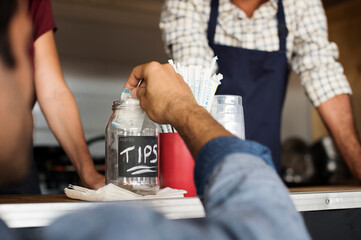 Close-up of customer putting tips in jar at food truck with vendors