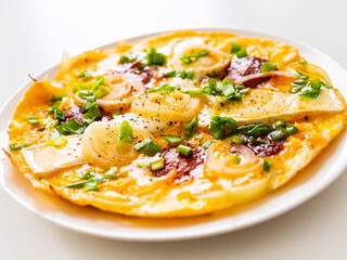 Delicious breakfast - scrambled eggs with onion, camembert and chorizo on wooden table
