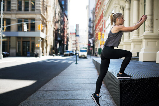 Female athlete exercising at sidewalk in city