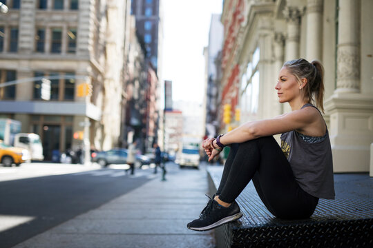 Thoughtful athlete relaxing at sidewalk in city