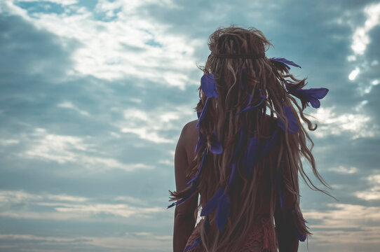 Rear view of woman with dread locks against cloudy sky