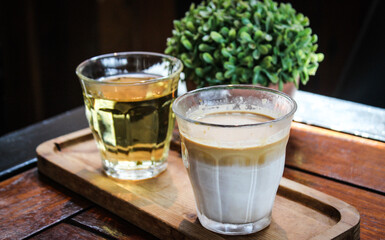 butterscotch dirty coffee with creamy white milk and espresso in transparent glass on wooden tray on wooden table in coffee shop cafe