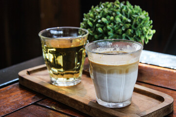 butterscotch dirty coffee with creamy white milk and espresso in transparent glass on wooden tray on wooden table in coffee shop cafe
