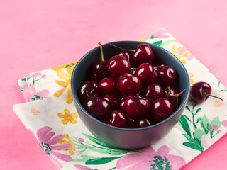 Fresh summer cherries in bowl on pink napkin background.