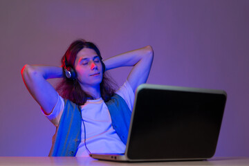 Gamer or programmer at a laptop, portrait in neon light. Take a break from work,