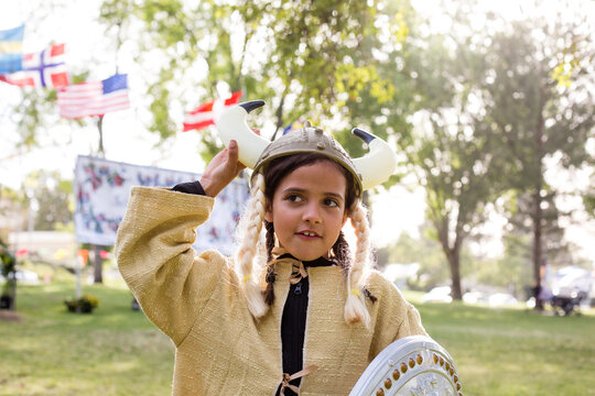 Girl adjusting viking helmet while standing in park
