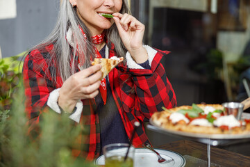 Beautiful matured asian woman is eating pizza in cafe terace