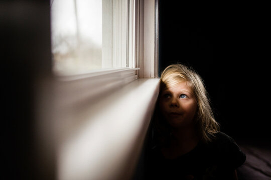 Thoughtful girl looking through window while sitting at home