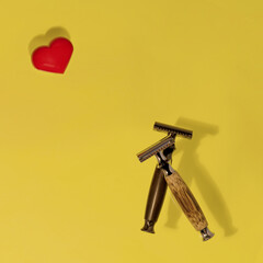 two razors and red heard on yellow background. View from above.