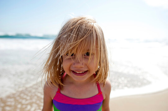 Close-up portrait of smiling girl standing on shore at beach