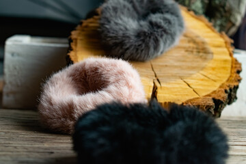 Fashionable and stylish fur elastic bands for hair and hairstyles. Multi-colored artificial and natural cannons on a natural wooden background