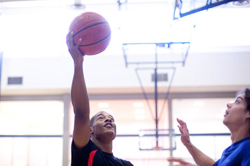 Basketball players playing in brightly lit court