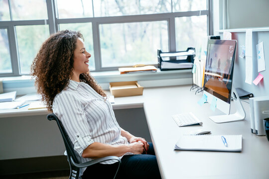 Side view of smiling businesswoman looking at desktop computer in office