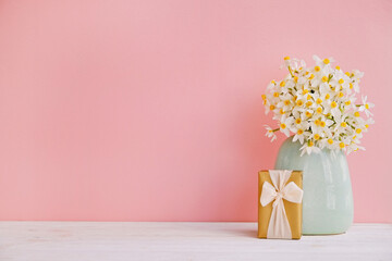 Lush bouquet of white-yellow daffodils in vintage turquoise vase isolated on pink background. Tender minimalistic spring flowers composition. Top view, copy space for text, flat lay, close up.