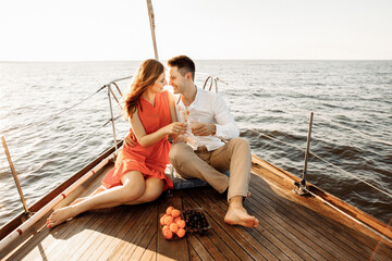 Fototapeta na wymiar Lovely couple in love on a yacht drinking champagne, luxury rest on the ship.