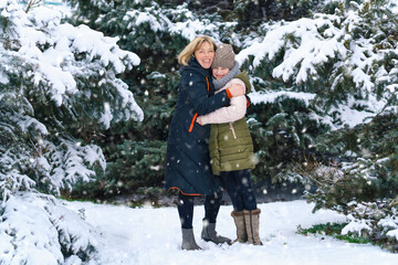 Fototapeta na wymiar mother and daughter family portrait in a winter forest, one parent and one children, beautiful nature with bright snowy fir trees