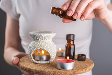 A woman is dripping organic essential oil into an aroma lamp for a relaxing and pleasant...