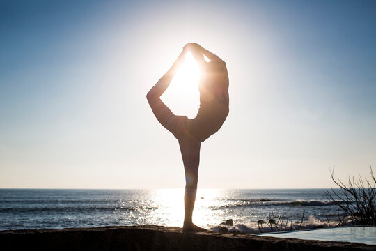 Woman practicing Shiva posture against sea and clear sky during sunny day