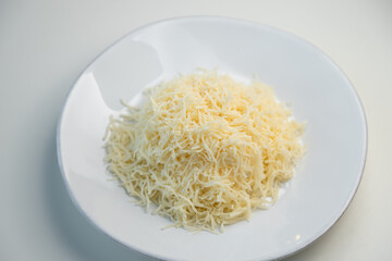 Grated cheese on a white plate close-up. Grated cheese salad, restaurant serving of the dish.