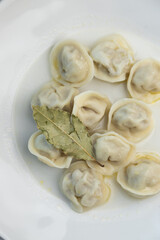 Meat dumplings on a white plate with bay leaf. Restaurant serving dishes, close-up.