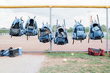 Baseball bats in bags hanging on chainlink fence at playground