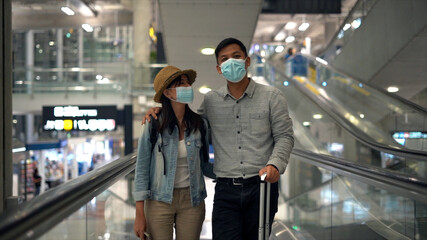 Couple Asian people walking in airport terminal waiting for  flight boarding.