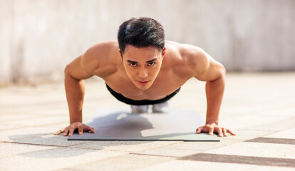 Fototapeta na wymiar Fitness asian young handsome man doing push ups exercise