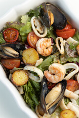Sea salad with mussels, shrimps and squid rings with vegetables. Restaurant dish with seafood close-up.