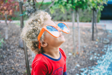 Playful boy in sunglasses looking up