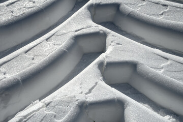 Close up of wide deepened tracks of tires of tractor in fresh soft white snow with high contrast