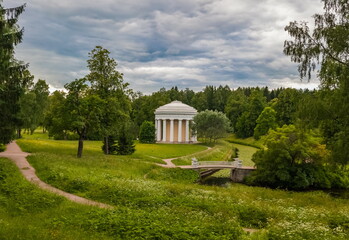 Obraz premium Summer landscape in the city Park with trees, pavilion, stone bridge over the river, sky with clouds
