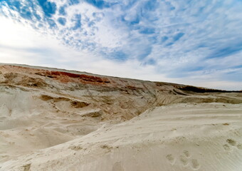 Mountains of sand against a blue sky with clouds
