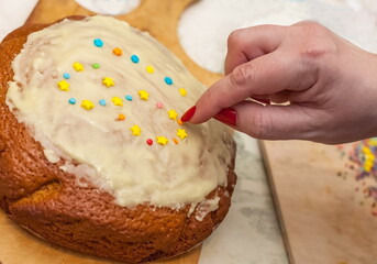 Glazed cake with lined pastry figures figures on a wooden cutting Board and a woman's hand close up