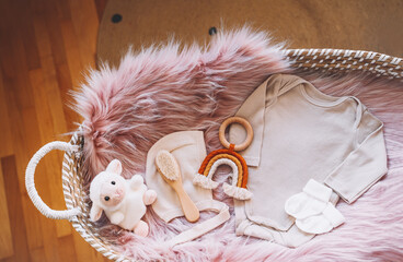 Newborn background. Baby changing basket with baby bodysuit, soft plush sheep and natural wooden toy. Still life of child products. Minimalist style photography of baby shower, pregnancy announcement.