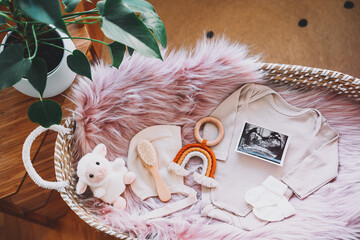 Baby changing basket with ultrasound image, baby bodysuit, soft and wooden toys. Still life of...