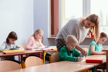 Fototapeta premium Young blonde haired teacher with children in the classroom