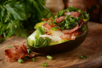 Baked avocado and eggs boats with bacon crumbles . Low carb high fat breakfast